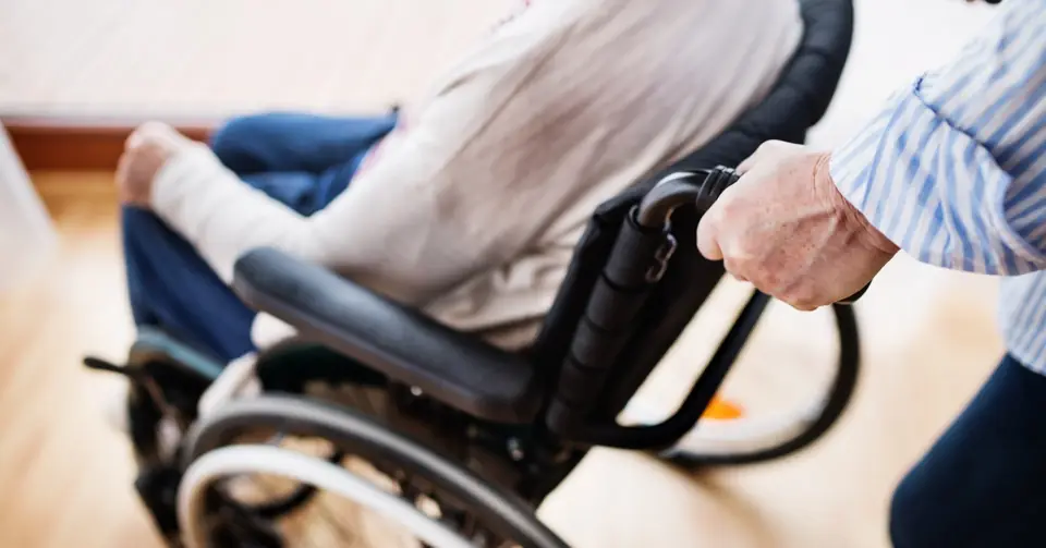 Senior im Rollstuhl wird nach Hause begleitet