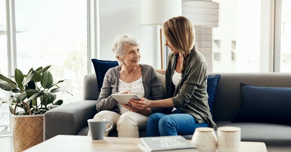 Beraterin im Gespräch mit Seniorin auf dem Sofa